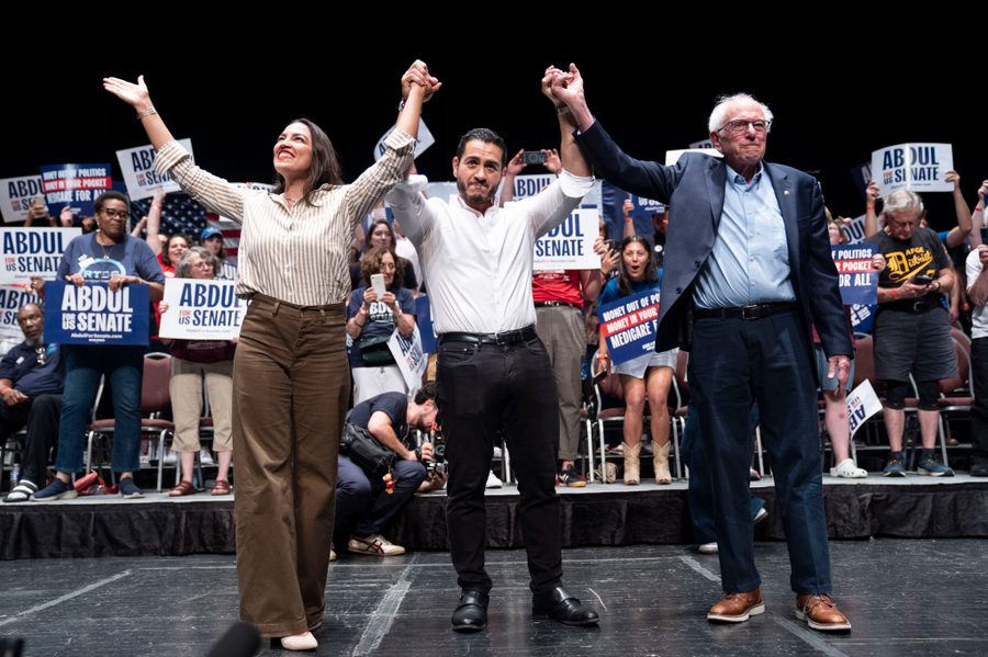 Abdul El-Sayed on stage with Alexandria Ocasio-Cortez and Bernie Sanders, raising their joined hands